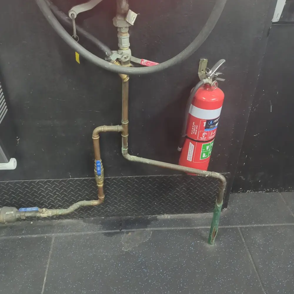 The member's photo of the burst fire hose reel pipe, with water on the floor beneath it